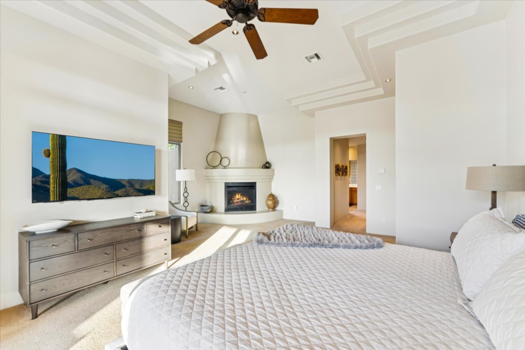 Sunny bedroom with a cozy fireplace and views of the hills.