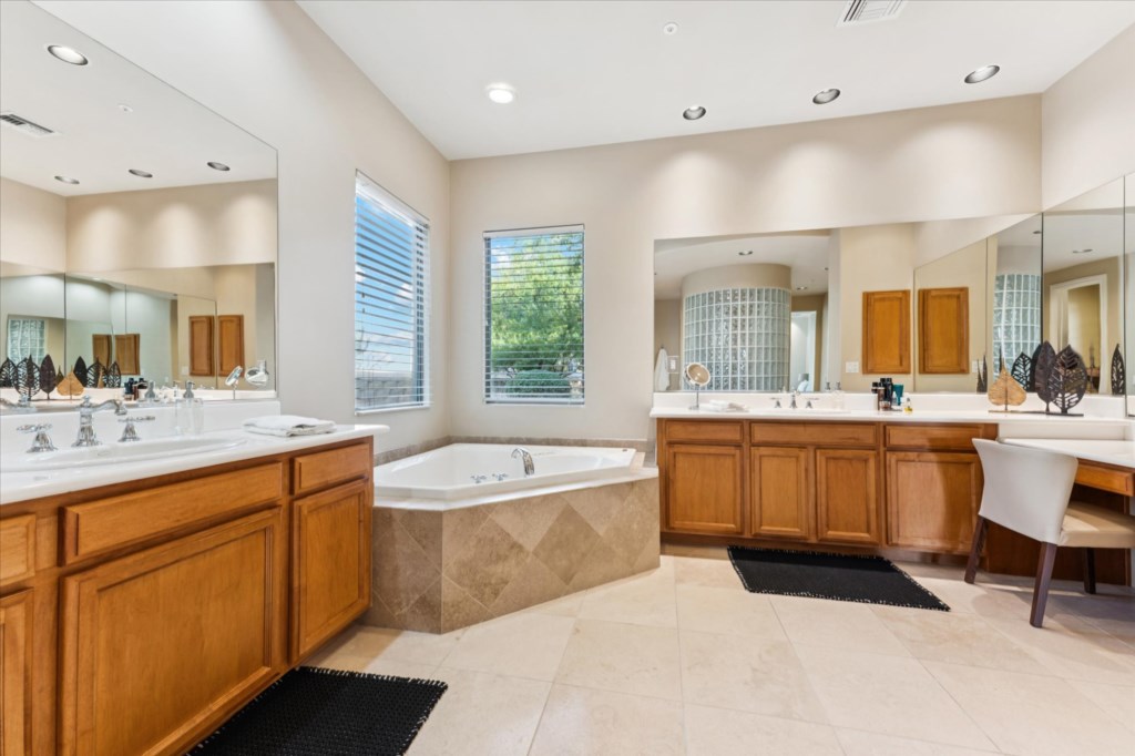 Spacious bathroom with large tub, dual sinks, and ample natural light.