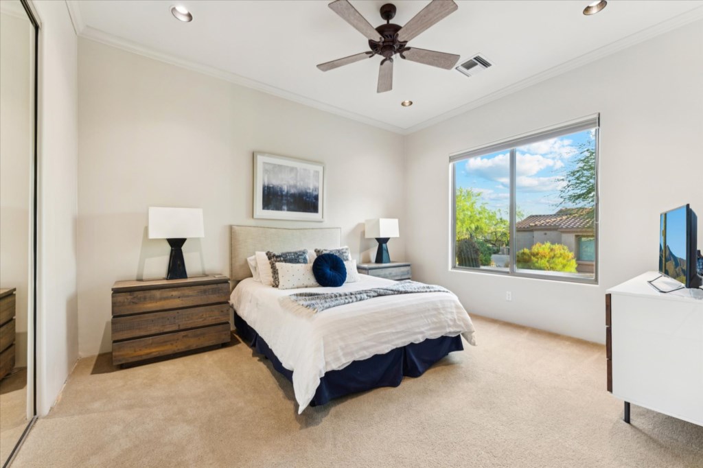 Serene bedroom with large windows overlooking a sunny landscape.