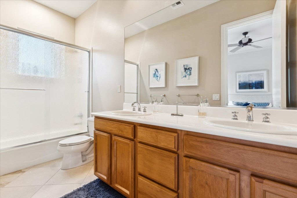 Bright bathroom with dual sinks, large mirror, and spacious shower.