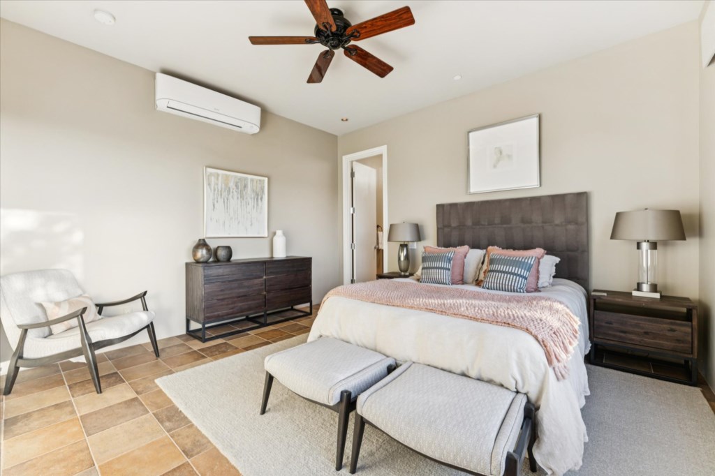 Sunny bedroom with a plush king bed, tiled floors, and a cozy sitting area.