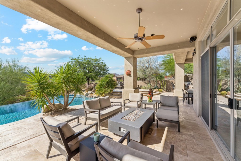 Covered patio with stylish seating and pool view, perfect for relaxing outdoors.