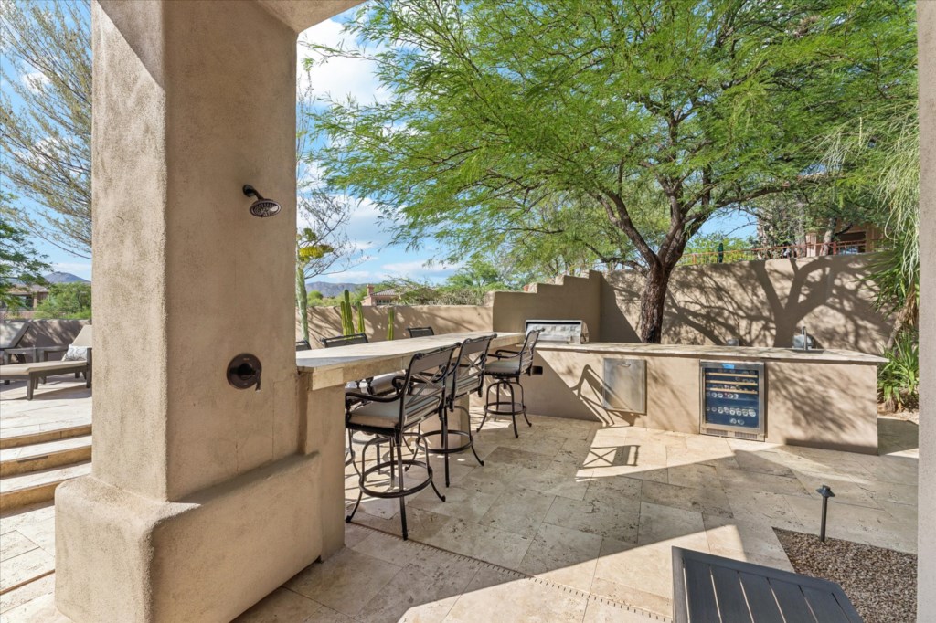 Patio with outdoor dining set, surrounded by desert plants and clear skies.