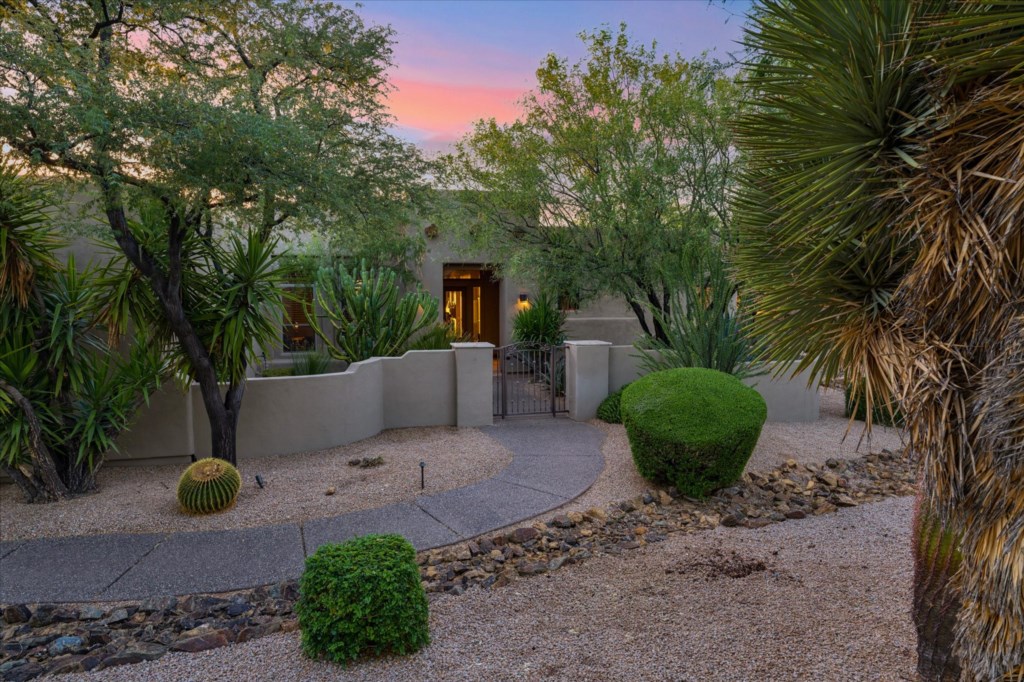 Charming entrance with native landscaping, welcoming twilight ambiance.