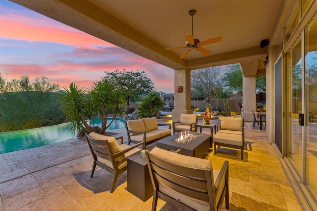 Covered patio with dining area and view of the sunset-lit pool.