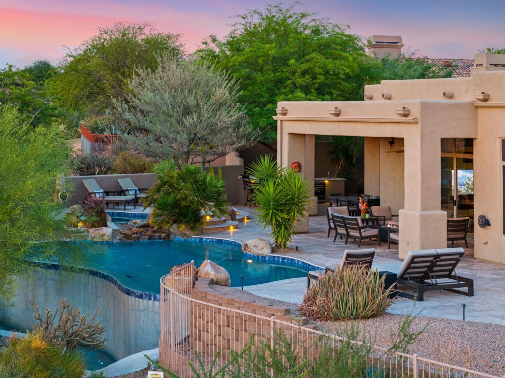 Desert oasis with a heated pool, lounge chairs, and serene sunset views.