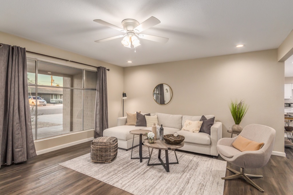 Modern living room with a large sectional sofa and stylish ceiling fan.