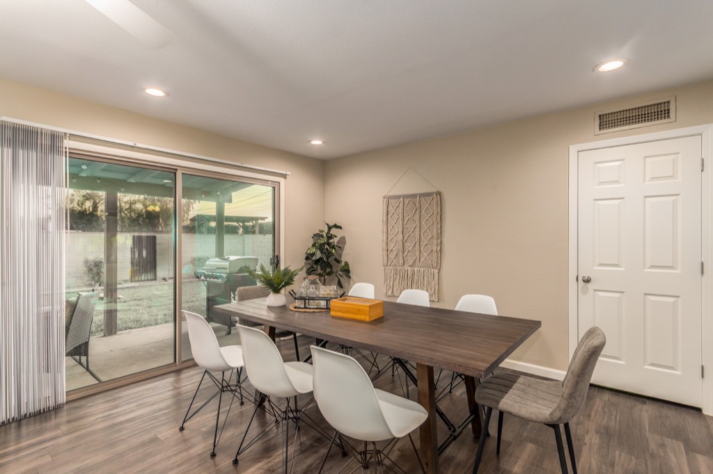 Spacious dining area with modern table, leading out to a sunny backyard.