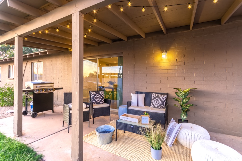 Covered patio with cozy seating, string lights, and a modern grill for relaxing evenings.
