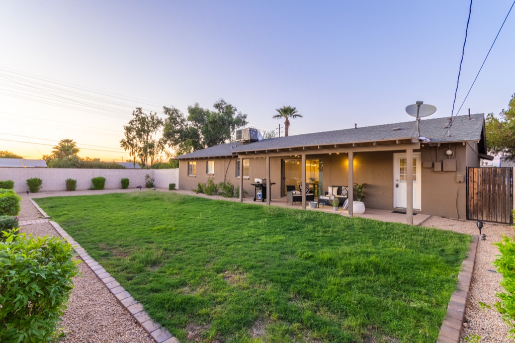 Spacious backyard with lush green lawn and a cozy patio, perfect for sunsets.