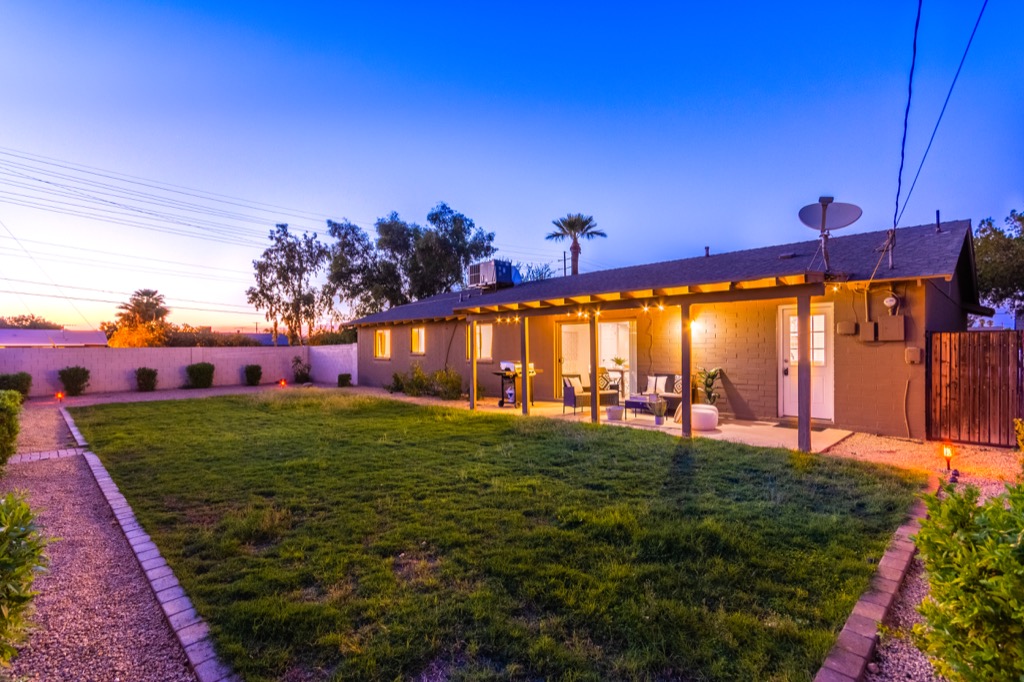 Tranquil backyard with lush lawn and comfortable patio seating at dusk.