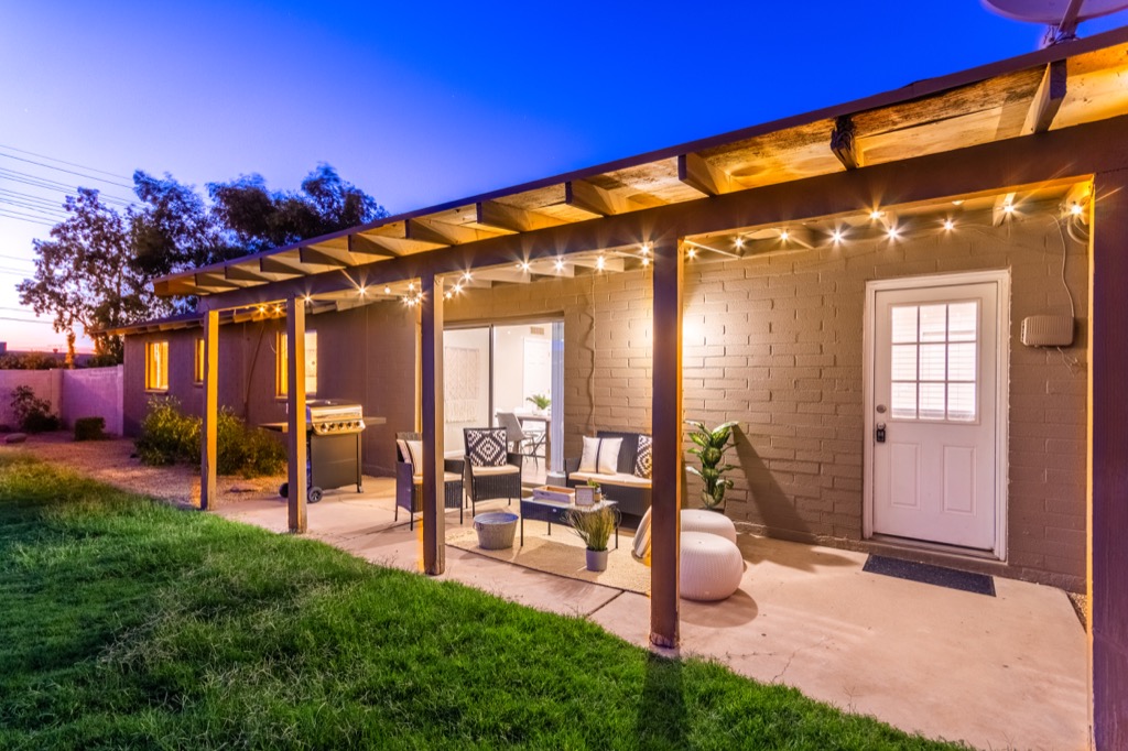 Inviting patio with string lights, BBQ grill, and cozy seating area.