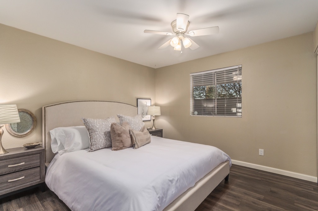 Serene bedroom with elegant linens and modern ceiling fan, great for relaxation.