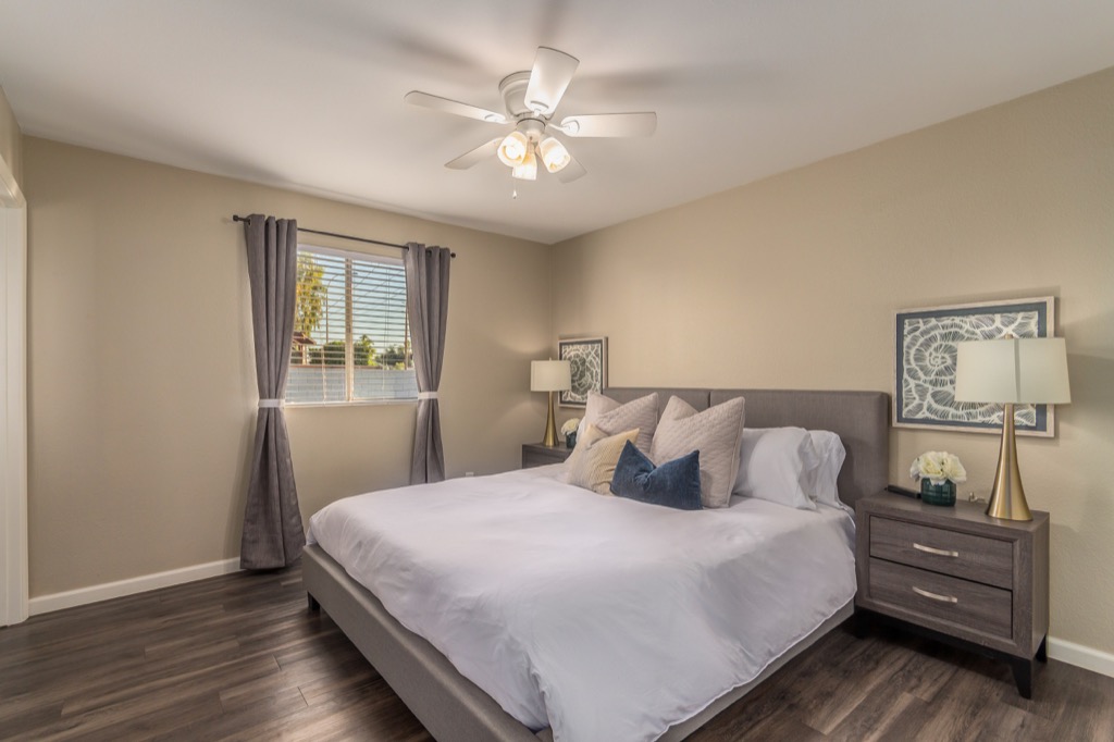 Serene master bedroom with plush bedding and modern ceiling fan.