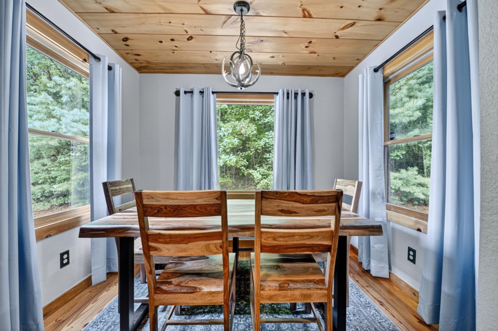 Rustic dining area with natural wood table and forest views.