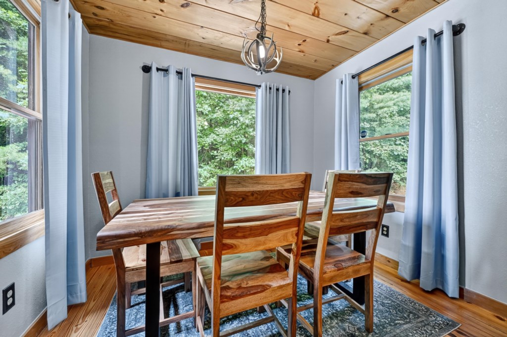 Rustic dining area with natural wood table and forest views.