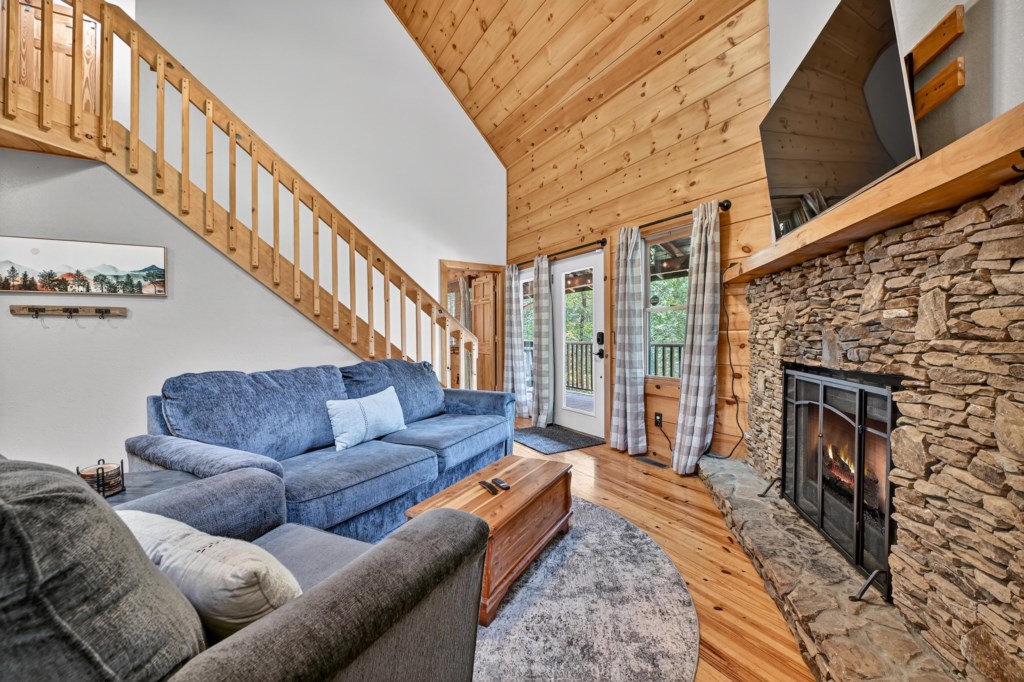 Cozy living area with stone fireplace and access to outdoor deck.