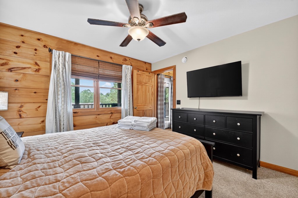 Rustic bedroom featuring a queen bed, wooden walls, and scenic views.