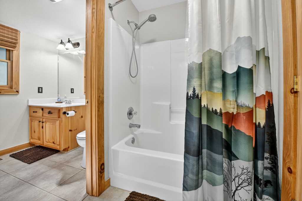 Bright bathroom with artistic shower curtain and wooden vanity.