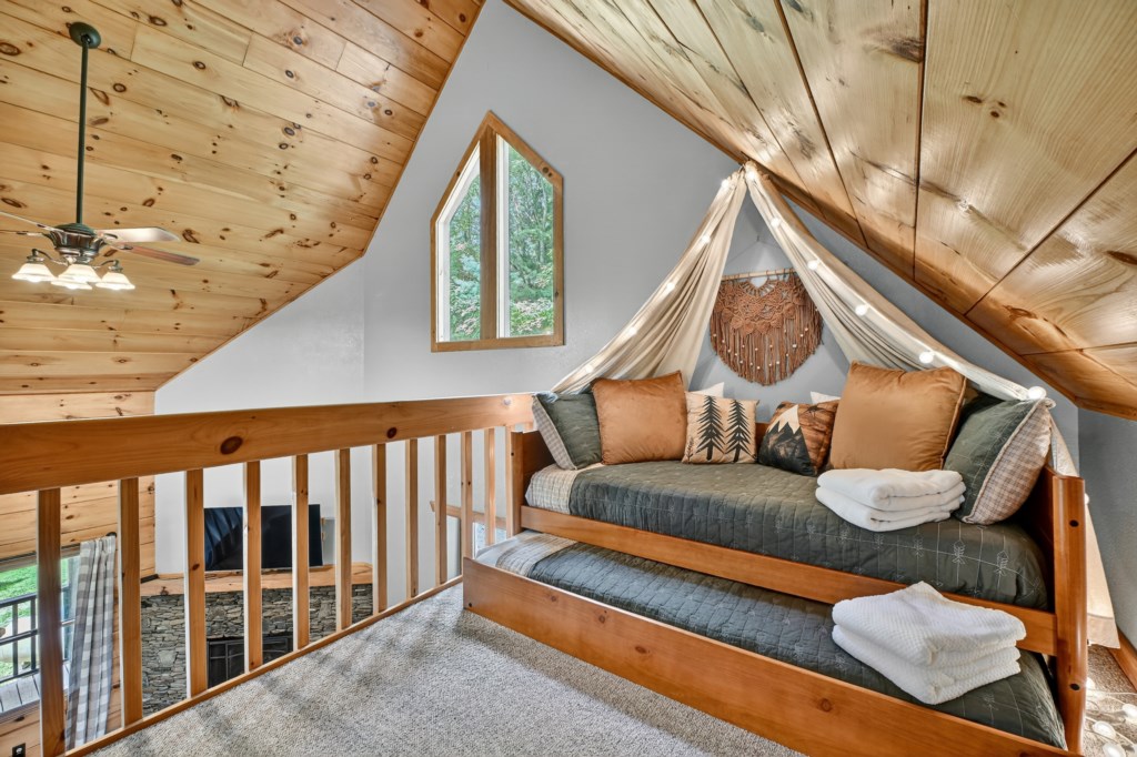 Loft bedroom with a cozy window nook and rustic wooden details.