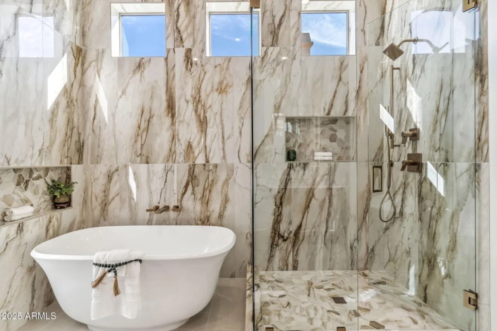 Luxurious marble bathroom with soaking tub and glass-enclosed shower.