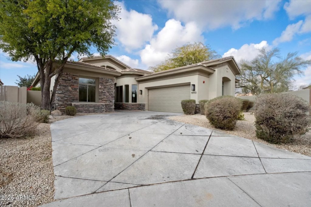 Charming desert home with spacious driveway and beautiful stone accents.