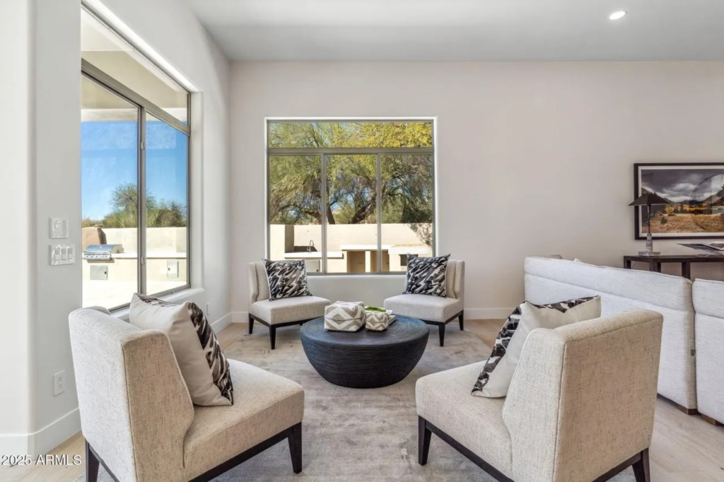 Bright living room with modern seating and large windows offering natural light and scenic views.