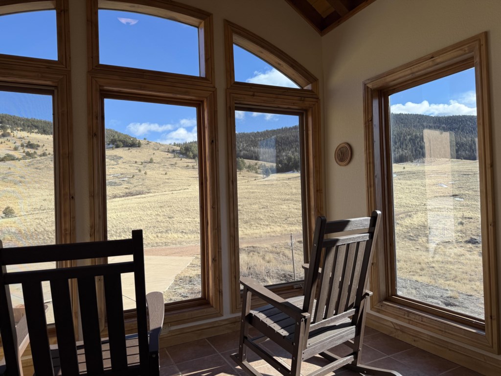 Sunroom with 2 rocking chairs that overlook the property. It is a perfect place to enjoy a cup of coffee.