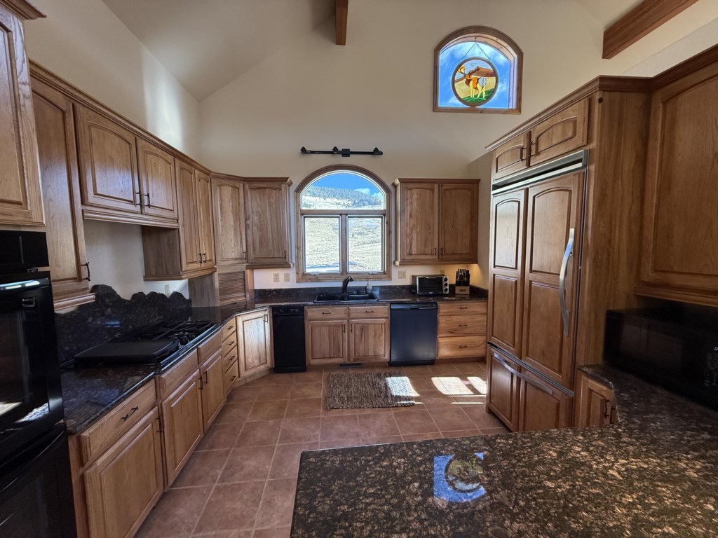 Chef's kitchen fully equipped with double oven, dishwasher, gas stove, and large refrigerator. 