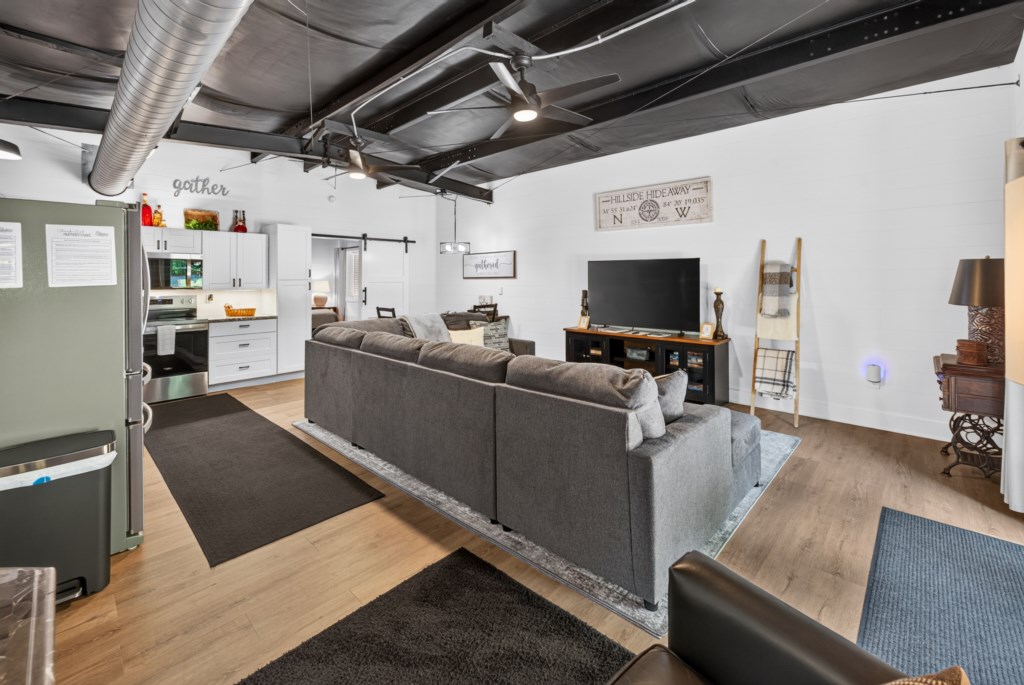 Spacious living area with cozy seating and open kitchen, perfect for gatherings.