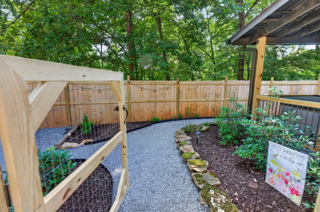 Charming garden path with lush greenery and cozy fenced area for relaxation.