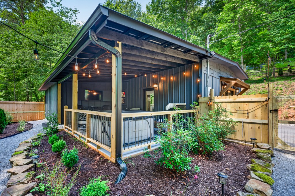 Charming outdoor patio with string lights, perfect for evening relaxation in a wooded setting.