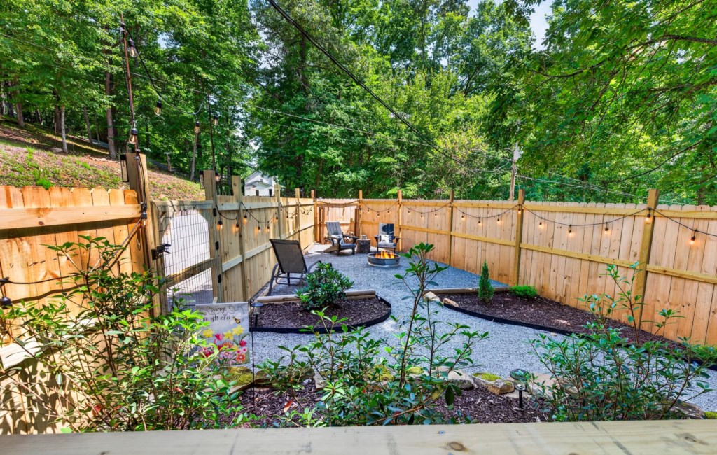 Charming fenced backyard with cozy fire pit and string lights for relaxing evenings.