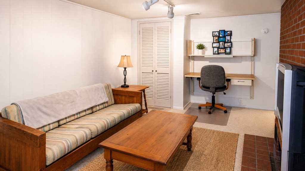 Lower-level lounge with futon, desk and dedicated workspace for longer stays.