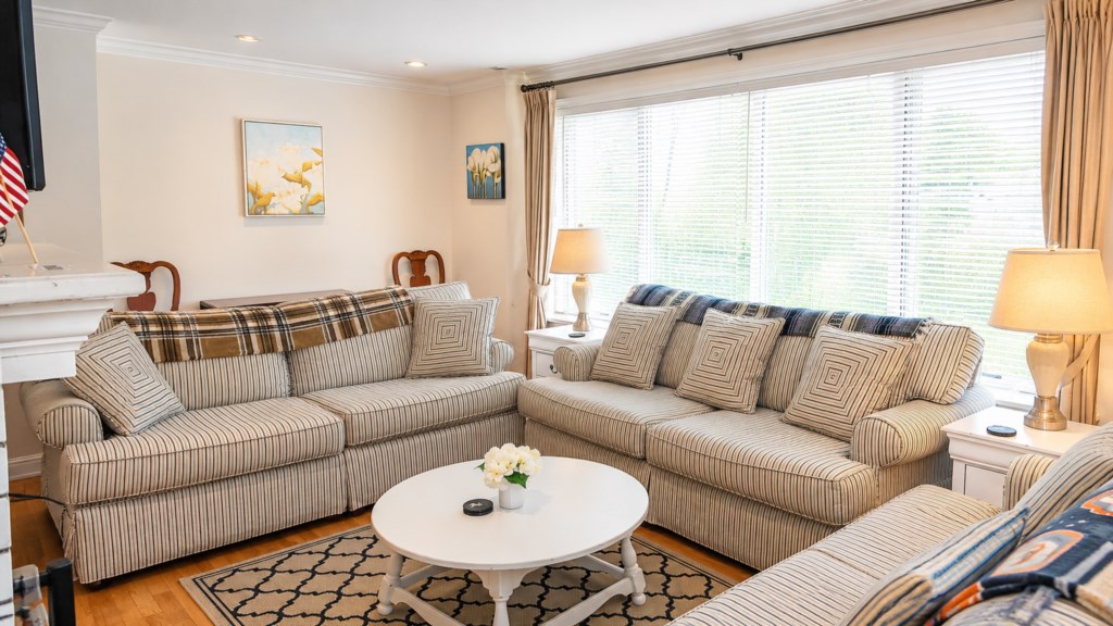 Bright living room with generous seating and large windows overlooking the yard.