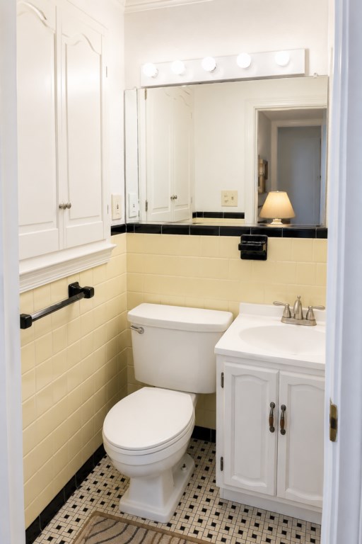 Full bath with vintage yellow tile, vanity, storage and shower nearby.