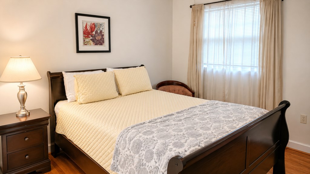 Welcoming queen bedroom with crisp bedding, bedside lamp and natural light.