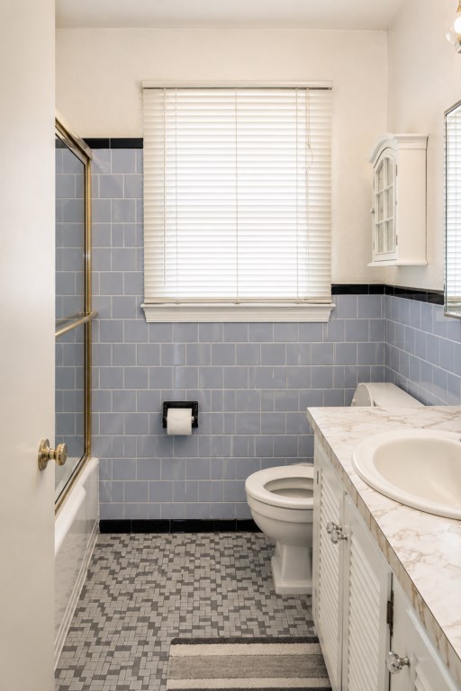 Full bath with blue tile, shower, vanity and original mid-century character.