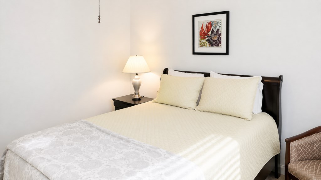 Comfortable queen bedroom with warm bedding, nightstand and natural light.