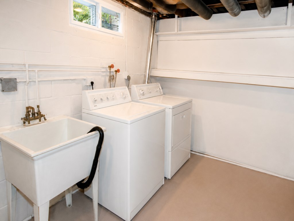 Private laundry area with washer, dryer and utility sink for guest use.