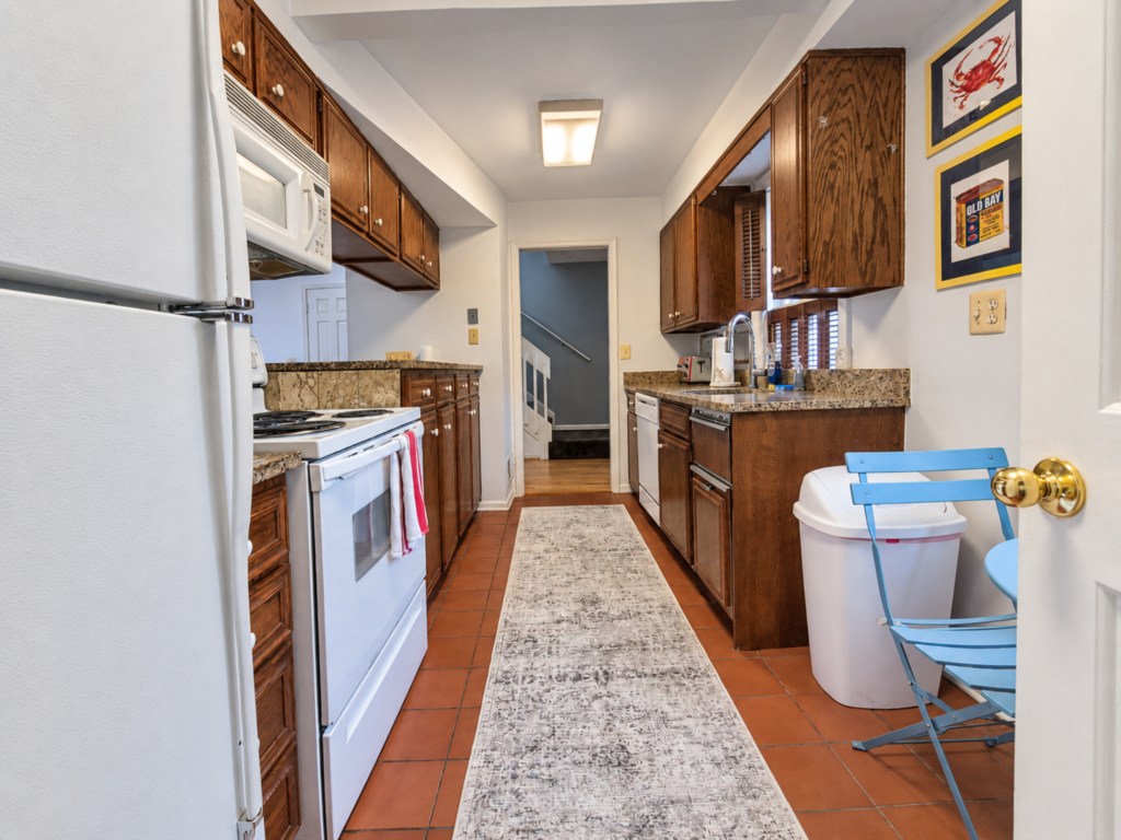 Galley kitchen with wood cabinetry and tile flooring.