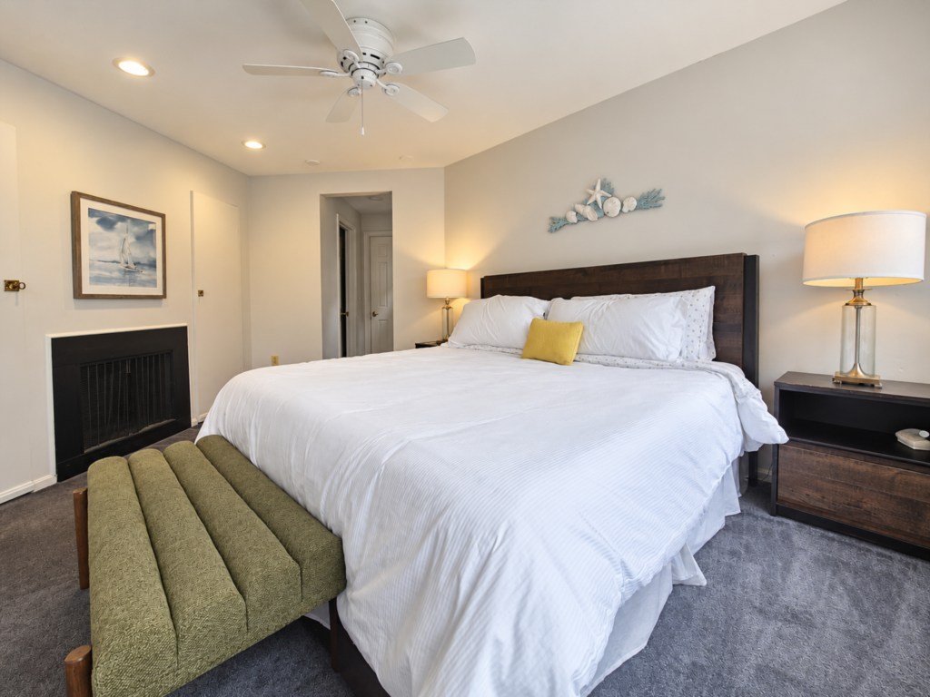 Primary bedroom with crisp white bedding and an upholstered bench.