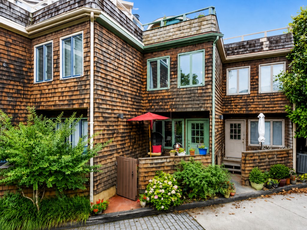 Shingle-clad exterior with colorful flowers and greenery.