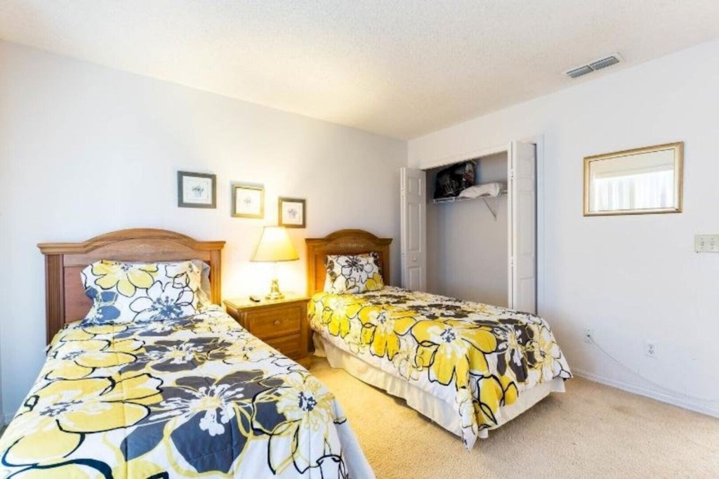 Cozy third bedroom featuring two comfortable twin beds and a closet to keep all your items stored