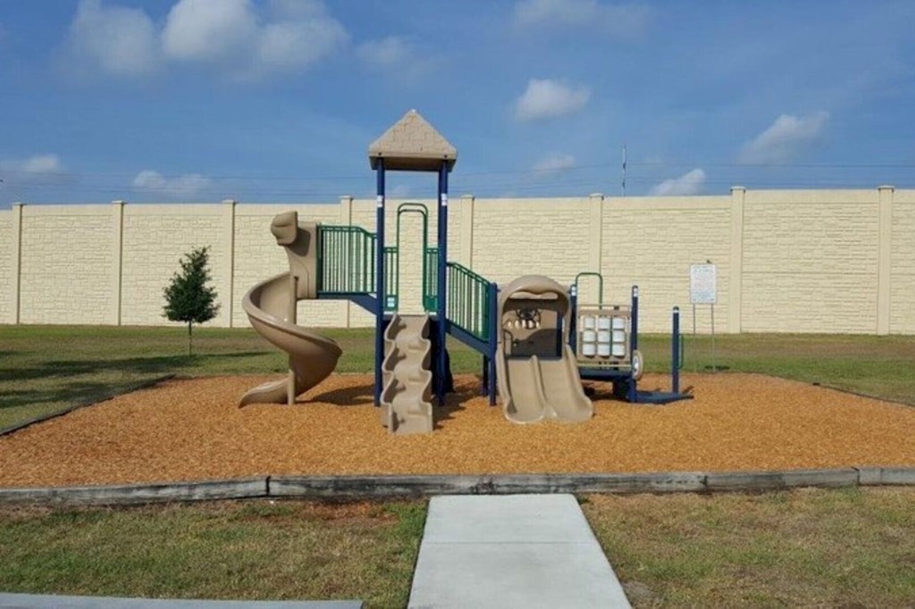 Community children's playground featuring a variety of play equipment, seating areas, and well maintained walking paths