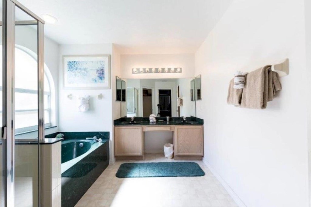 Large master en-suite bathroom featuring a spacious walk-in glass shower, dual vanity sinks, soaking tub
