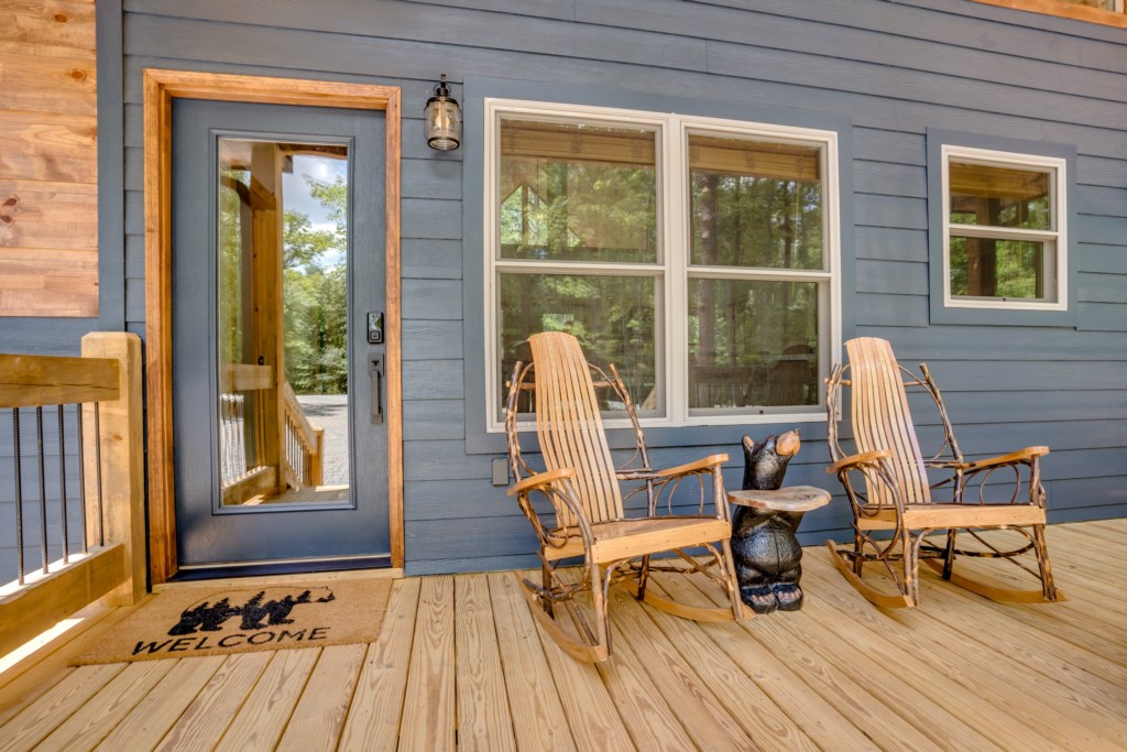 Charming front porch with rustic rocking chairs and woodland views.