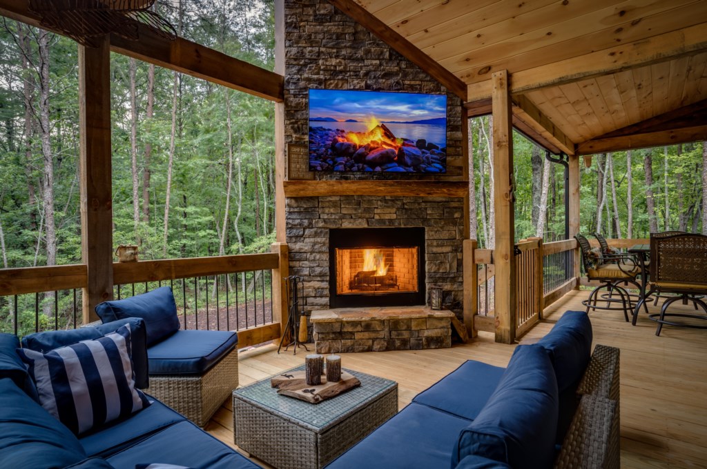 Cozy outdoor lounge with fireplace and forest views, perfect for relaxation.