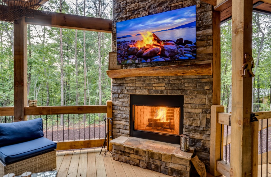 Cozy outdoor lounge with fireplace and forest views, perfect for relaxing evenings.