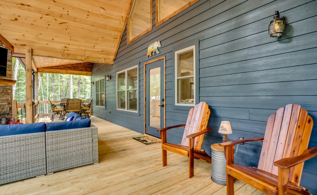 Spacious covered deck with cozy seating and forest views, perfect for relaxing afternoons.
